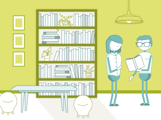 two employees talking about a book in the office in front of the bookshelf